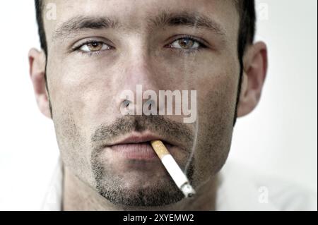 Portrait of a young man with a smoking cigarette in his mouth Stock Photo