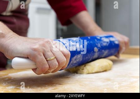 Hands guide rolling pin and roll out dough Stock Photo