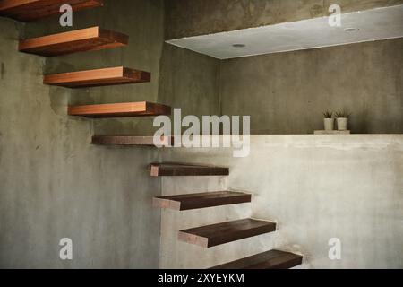 Floating wooden stairs and wall niches in a minimalist industrial concrete interior Stock Photo