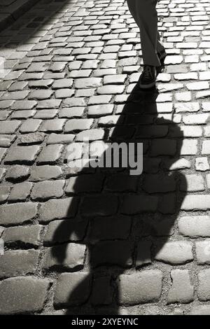 Shadows of oncoming people on cobblestones against the light Stock Photo