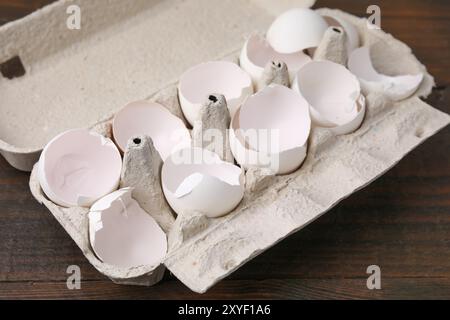 Broken eggshells in carton on wooden table, closeup Stock Photo