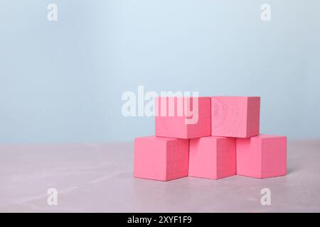Blank pink cubes on light grey marble table, space for text Stock Photo