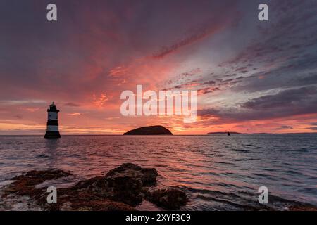 Colourful dawn sky over Trwyn Du lighthouse and Puffin Island at Penmon Point, Anglesey North Wales Stock Photo