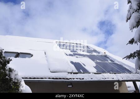 Snow-covered solar system on a house in winter. Solar system in winter with snow on the roof Stock Photo