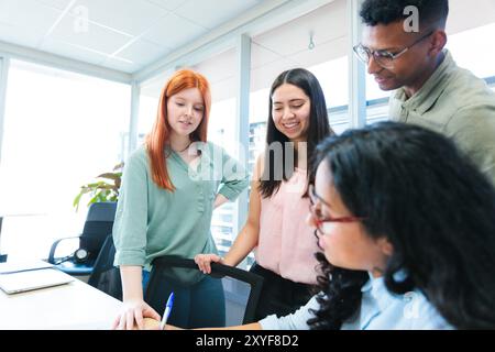 Multiethnic teamwork collaborating on business strategies, standing around a table and brainstorming in a modern office Stock Photo
