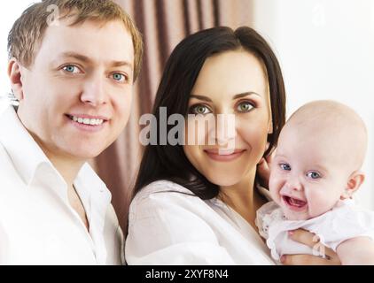 Happy smiling family with little baby girl indoor Stock Photo