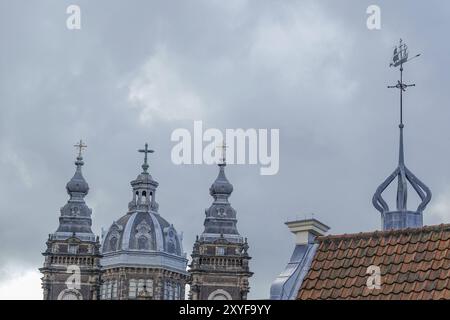 Church spires and a roof with weather vane under a cloudy sky, Amsterdam, Netherlands Stock Photo