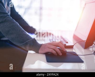 Male hand holding computer mouse with laptop keyboard in the background Stock Photo