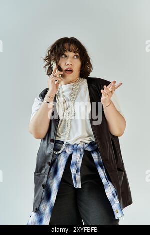 Woman in colorful outfit with pearl necklace looks surprised talking on phone Stock Photo