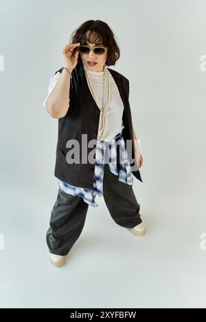 A woman in a black vest and plaid shirt stands confidently with her sunglasses on. Stock Photo