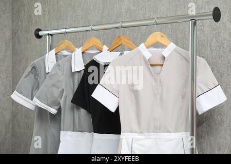 Maids' uniforms on clothing rack near grey wall Stock Photo