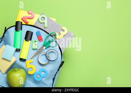 Light blue school backpack with stationery on green background, top view. Space for text Stock Photo