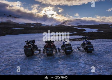 ICELAND, JULY 04: Four snow mobiles parked in a row in thick winter snow in Iceland in a desolate freezing cold wintry landscape on July 04, 2013 in I Stock Photo