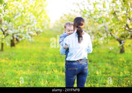 Little baby boy with his young mother in the blossoming spring garden Stock Photo