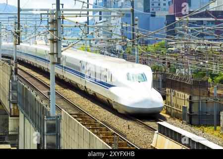 KYOTO, JAPAN, JUNE 21, 2015: Approaching Shinkansen bullet train on high elevated rails surrounded by wires seen from above aerial view leaving city o Stock Photo