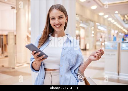 Young Caucasian woman smiling widely while looking at camera and holding phone Stock Photo