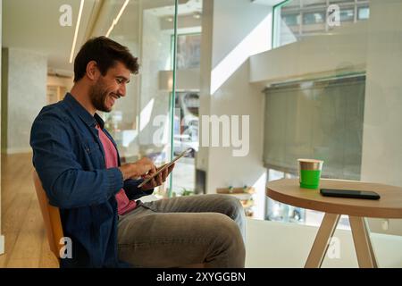 Young hispanic man stopping taxi with hand raised up using smartphone at street Stock Photo