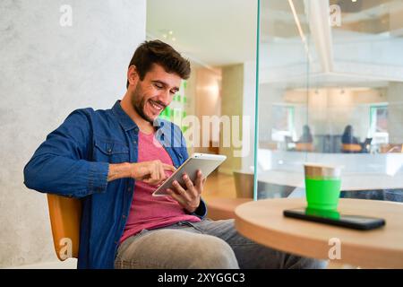 Young hispanic man stopping taxi with hand raised up using smartphone at street Stock Photo