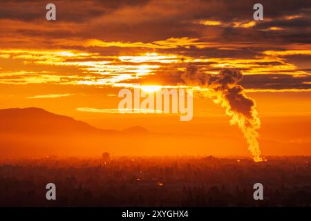 Industrial steam billowing into glowing sunrise above the San Fernando Valley in Los Angeles California. Stock Photo