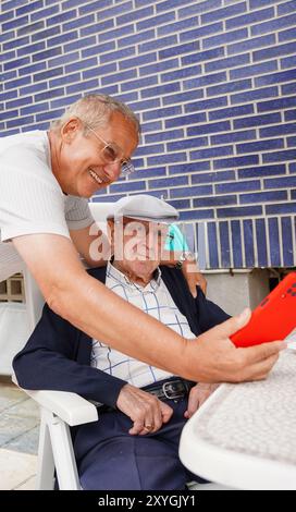 Father and son watching a video with their mobile in the terrace. Family men Stock Photo