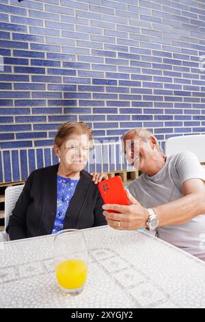 Elderly mother and her son looking at mobile. Family life Stock Photo