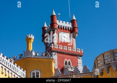 SINTRA, Portugal — The ornate red turret clock tower of Pena Palace stands out against the sky, showcasing the vibrant colors and eclectic Romanticist architecture of this 19th-century royal residence. This distinctive feature epitomizes the fairytale-like charm that makes Pena Palace a must-see landmark in Sintra. Stock Photo