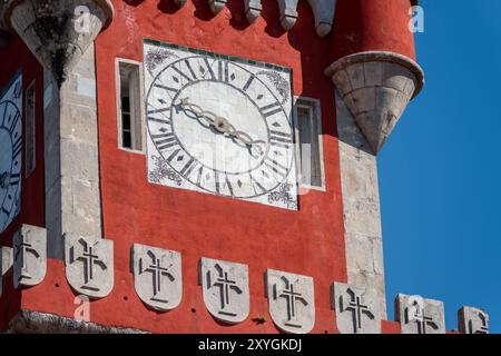 SINTRA, Portugal — The ornate red turret clock tower of Pena Palace stands out against the sky, showcasing the vibrant colors and eclectic Romanticist architecture of this 19th-century royal residence. This distinctive feature epitomizes the fairytale-like charm that makes Pena Palace a must-see landmark in Sintra. Stock Photo