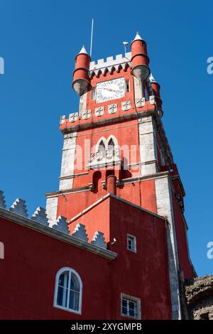 SINTRA, Portugal — The ornate red turret clock tower of Pena Palace stands out against the sky, showcasing the vibrant colors and eclectic Romanticist architecture of this 19th-century royal residence. This distinctive feature epitomizes the fairytale-like charm that makes Pena Palace a must-see landmark in Sintra. Stock Photo