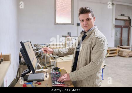 Operator Entering Coordinates on Computer for CNC Machine to Precisely Cut Wooden Pieces Stock Photo