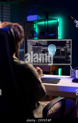 Programmer updating artificial intelligence neural networks, writing binary code scripts. Freelancing system administrator upgrading high tech AI in neon illuminated home Stock Photo
