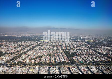 MEXICO CITY, Mexico — An aerial view of Mexico City sprawling across the dry lakebed of the Valley of Mexico. The dense urban landscape stretches to the horizon, illustrating the city's enormous scale and its precarious relationship with water resources. The visible lack of surface water bodies highlights the ongoing water crisis facing this megacity built on the site of the ancient Aztec capital of Tenochtitlan. Stock Photo