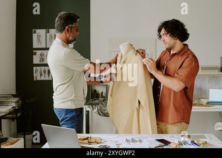 Biracial colleagues working on new female dress collection together in famous atelier Stock Photo