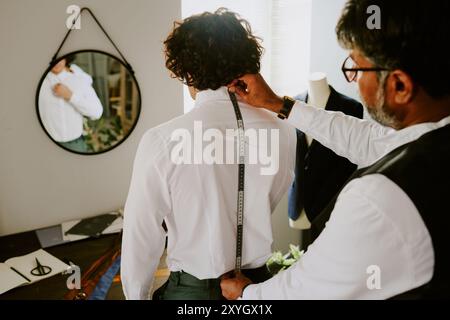 Unrecognizable tailor using measurement tape to take back measurements Stock Photo