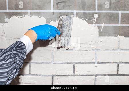Finishing the wall with gypsum plaster under decorative brick. Stage 2. Applying plaster to the wall with a spatula. Stock Photo