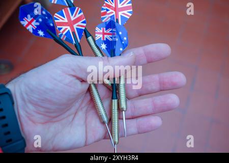 darts in a hand ready to play with them aiming at a bullseye Stock Photo