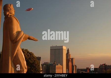 A sculpture of Roger Williams, founder of Providence RI, USA looks over the city skyline as a blimp passes by Stock Photo