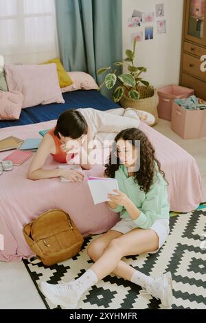 Two Women Studying Together in Cozy Bedroom Setting Stock Photo