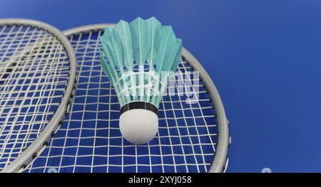 Yellow badminton feather shuttlecock on badminton racket over a blue background, banner size image with copy space Stock Photo