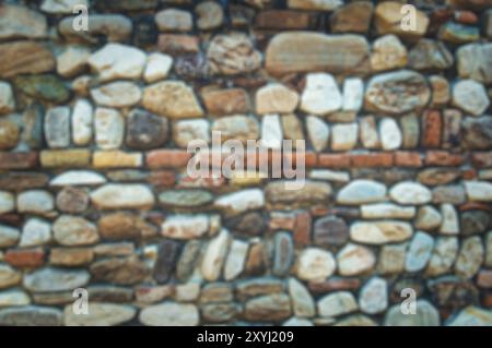 Ancient variegated stone wall out of focus Stock Photo