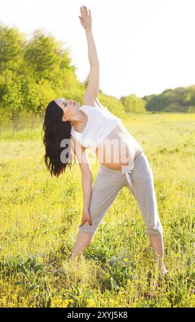 Healthy pregnant woman doing yoga in nature outdoors Stock Photo