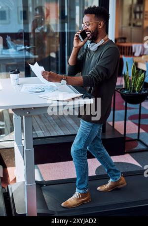African man, phone call and walking on treadmill for talking, fitness or health as speaker in modern office. Male person, mobile and working with Stock Photo