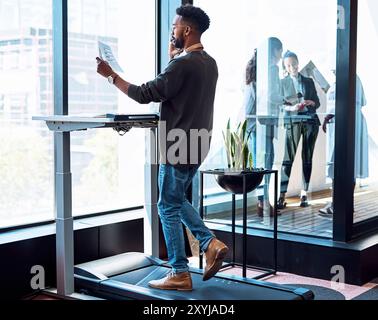 Black man, phone call and walking on treadmill for talking, fitness and health as speaker in modern office. Male person, mobile and working with Stock Photo