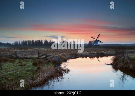 Pink sunrise over Dutch windmill and river, Groningen Stock Photo