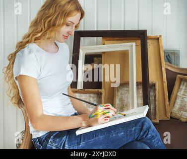 Portrait of female artist holding paintbrush in her studio Stock Photo
