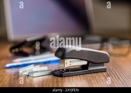 Black office stapler on a wooden table. Stock Photo