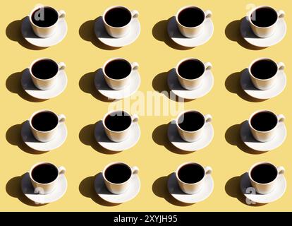 Pattern of white cup and saucer plate of black espresso coffee top view with shadow of sun on beige terracotta background. Stock Photo