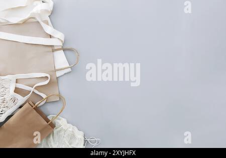 Flat lay with eco white craft paper bags and net bags on gray background with copy space empty advertising area. Packaging template mock up. Delivery Stock Photo