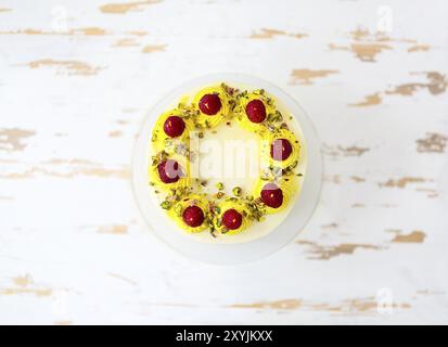 Beautiful happy birthday cake with mascarpone decorated with raspberry, pistachio and candles on the cake stand. Top view Stock Photo