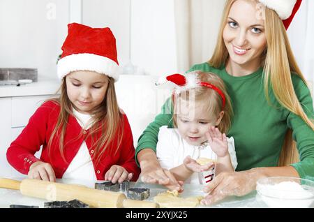 Two adorable girls with her mother baking Christmas cookies in the kitchen Stock Photo
