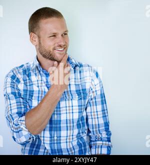 Handsome man, thinking or fashion with style or confidence in studio on a white background. Young, casual model or masculine male person with smile in Stock Photo